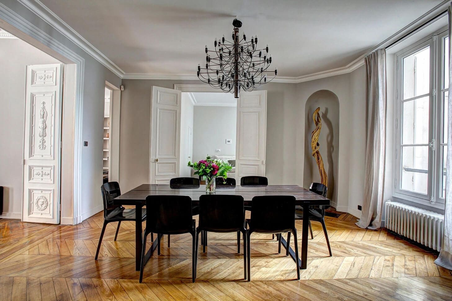 A dining room table with black chairs and a chandelier.